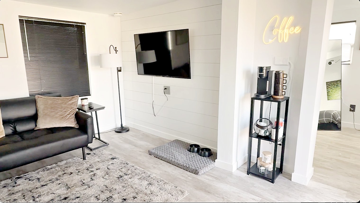 Living room with Smart TV, shiplap wall, and glowing coffee bar neon sign